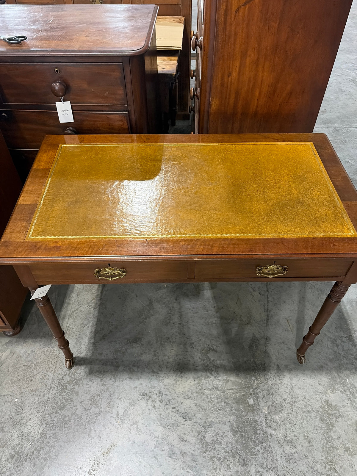 Edwardian ochre leather topped writing desk with two drawers and caster wheels