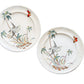 Two round ceramic plates with a vintage hand-painted design of a bird, palm trees, and butterflies, displayed on a rustic wooden background.