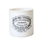 White ceramic jar with black text and design on a light wooden surface