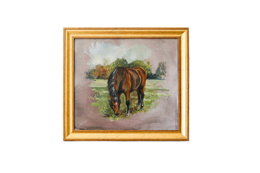 A framed painting of a brown horse grazing in a field, set in a distressed white wall with a marble surface below.