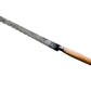 A vintage serrated bread knife with a long, weathered steel blade and a light brown wooden handle, resting diagonally on a textured off-white fabric background.