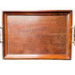 A rectangular wooden serving tray with a warm reddish-brown finish and two brass-and-wood handles, shown against a white textured fabric background.