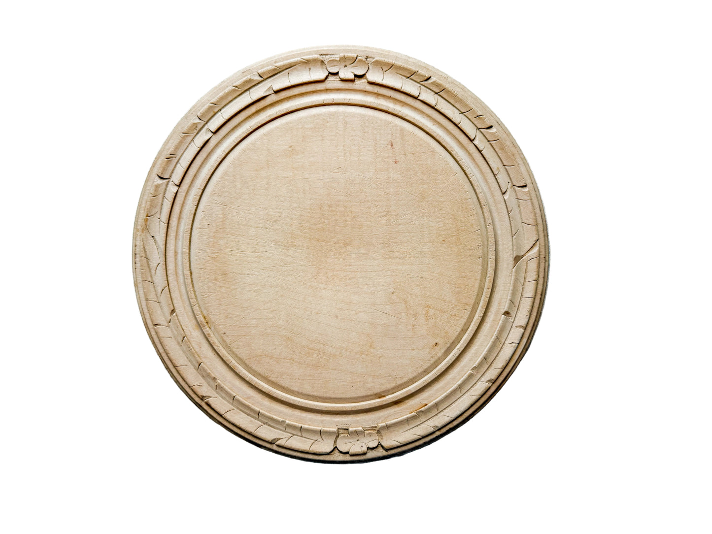 Round wooden cutting board with decorative edge on a light gray surface