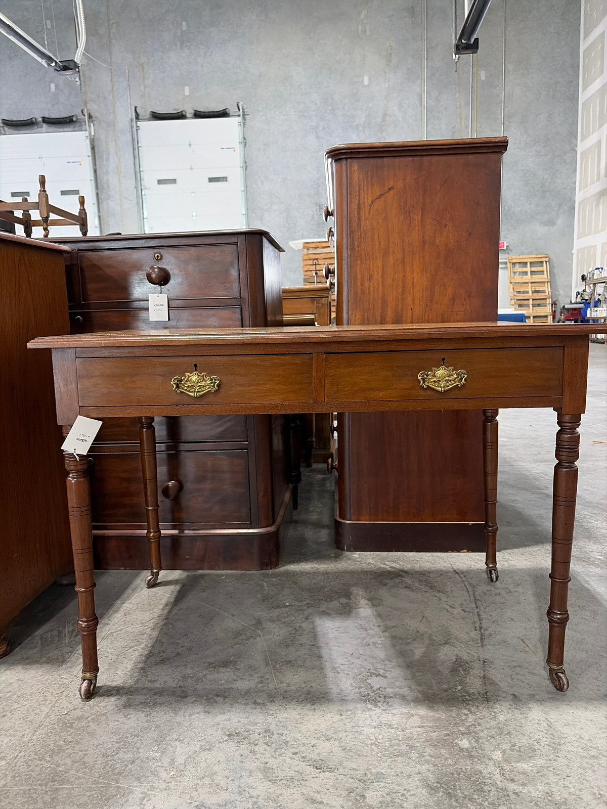 Edwardian ochre leather topped writing desk with two drawers and caster wheels