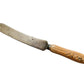 Old bread knife with a wooden handle on a light wooden surface