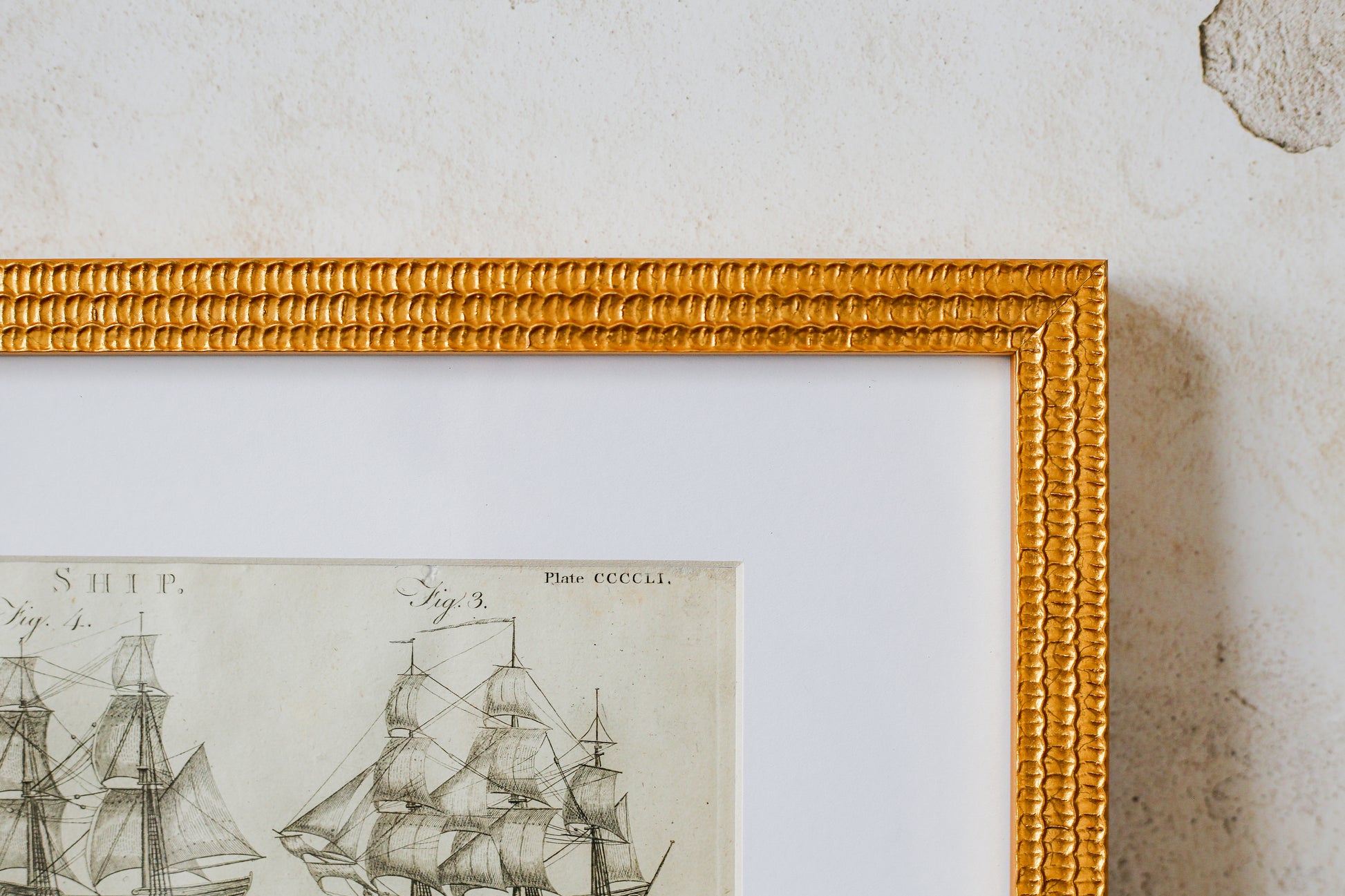Framed black and white ship illustration on a textured wall