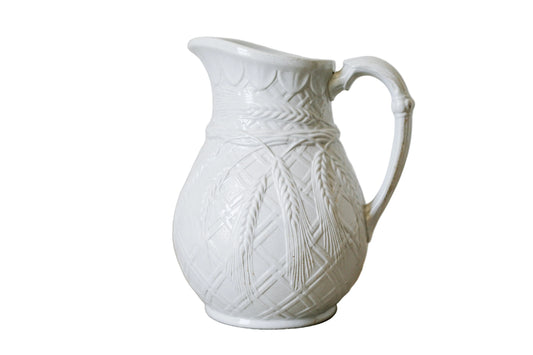 White ceramic pitcher with textured design on a wooden surface