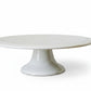 White ceramic cake stand on a marble surface with a light gray background