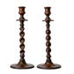 Two wooden candlesticks with twisted design on a textured wall background