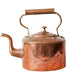 Copper kettle on a white surface with a light gray textured background