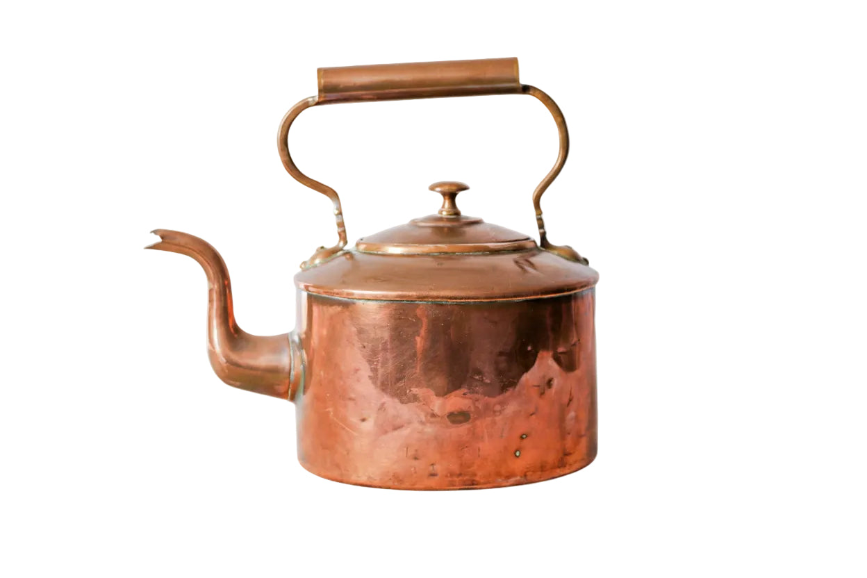 Copper kettle on a white surface with a light gray textured background