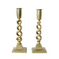 Two gold candle holders with twisted design on a light background
