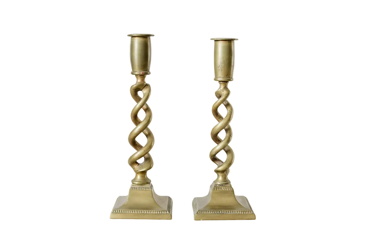 Two gold candle holders with twisted design on a light background