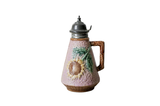 Majolica pitcher with sunflower design on a textured surface