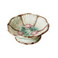 Footed majolica pedestal bowl with floral design on a textured surface