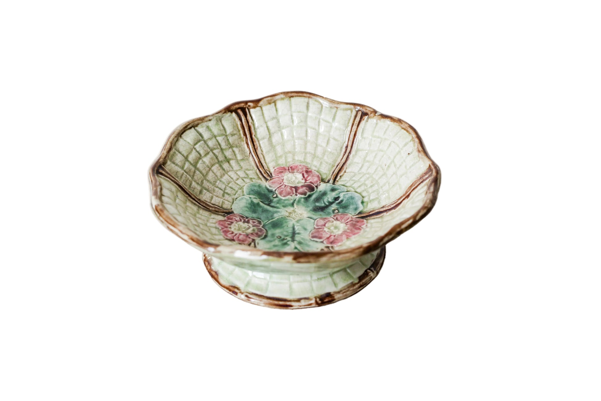 Footed majolica pedestal bowl with floral design on a textured surface