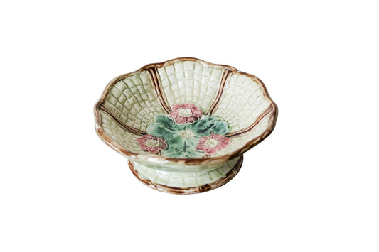 Footed majolica pedestal bowl with floral design on a textured surface