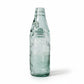 Vintage green glass bottle on a textured white surface