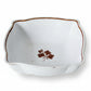 White ceramic dish with brown floral design on a textured beige surface