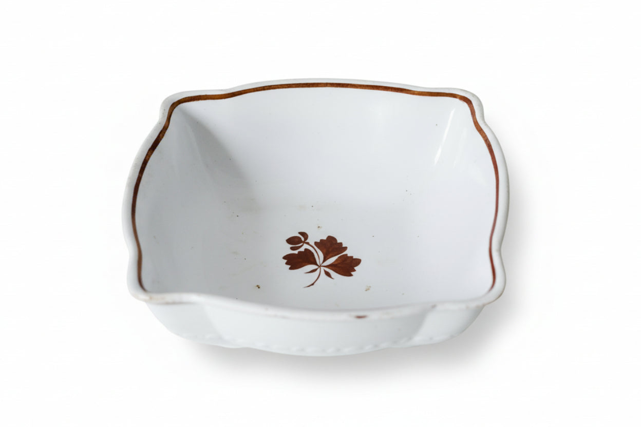 White ceramic dish with brown floral design on a textured beige surface