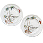 Two white ceramic plates with hand-painted tropical designs, including palm trees, birds, and butterflies, displayed on a rustic wooden plank background.
