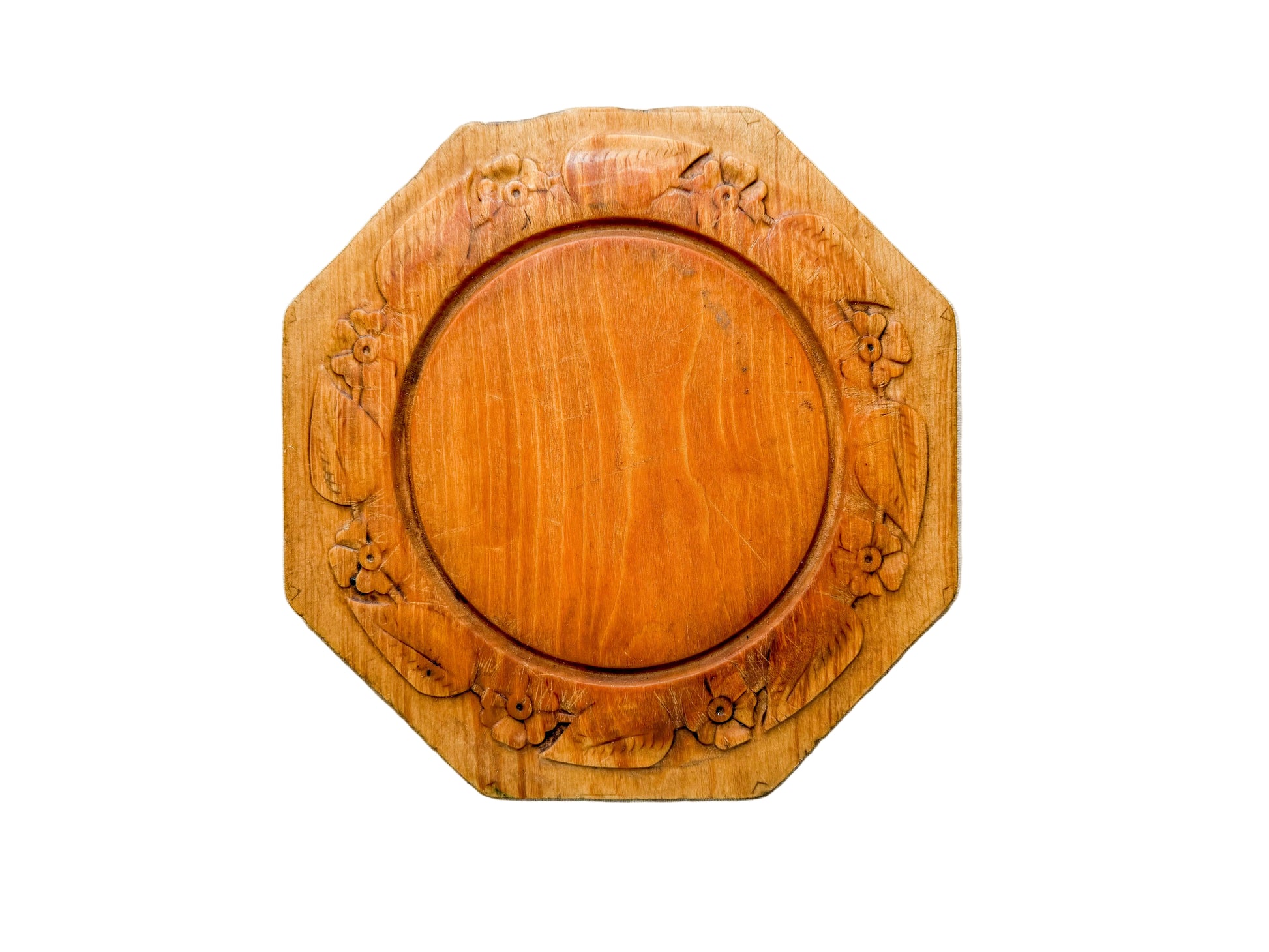 Wooden decorative plate with carvings on a light wooden surface