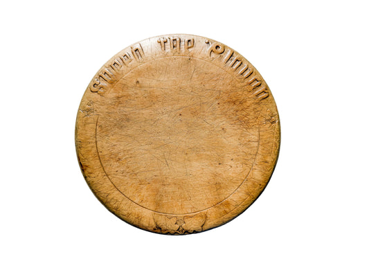 Round wooden cutting board with engraved text on a light gray surface