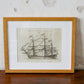 Framed black and white ship illustration on a textured wall