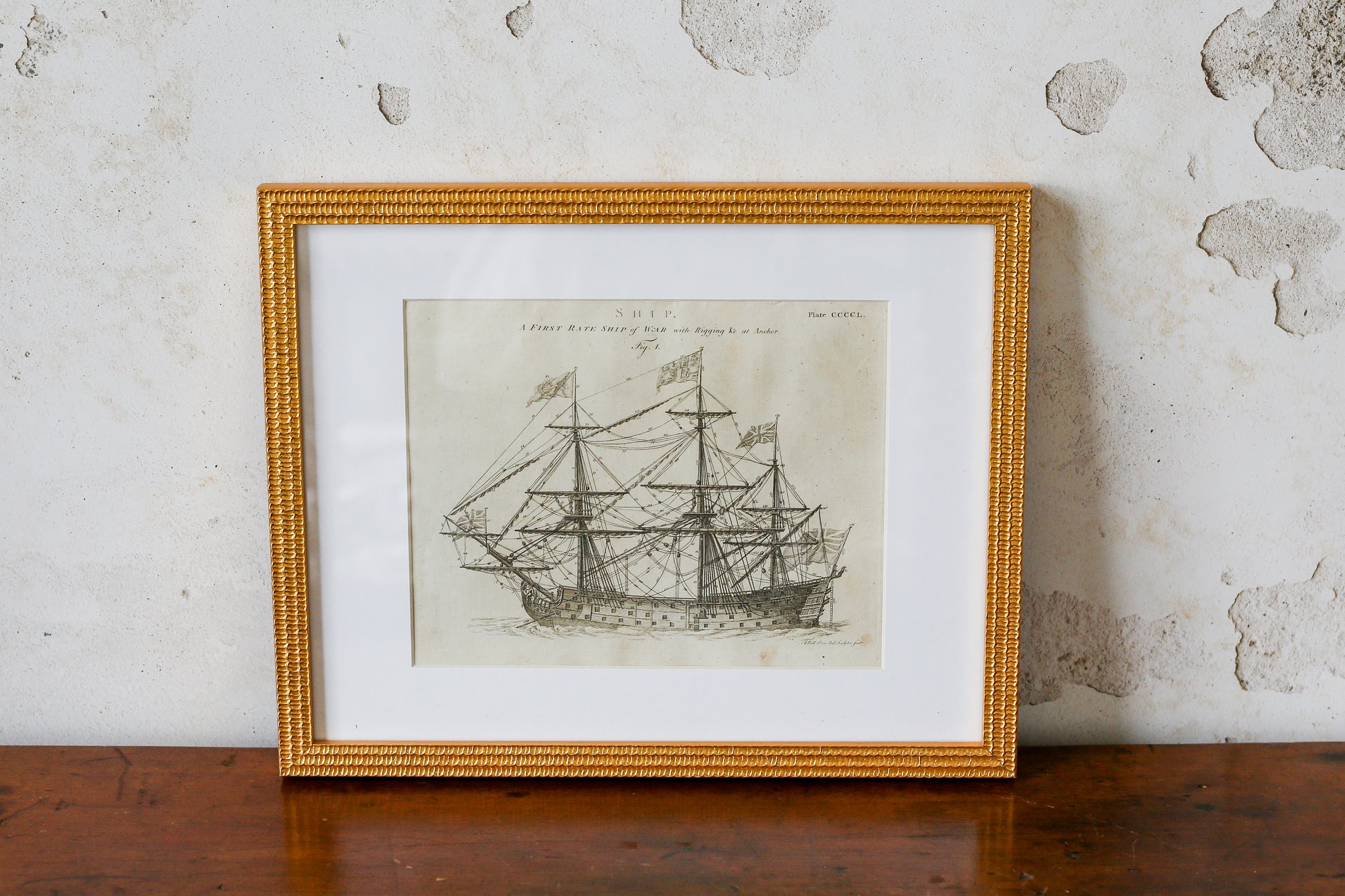 Framed black and white ship illustration on a textured wall