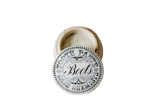 Metallic toothpaste cap with 'Boots' branding on a textured beige background