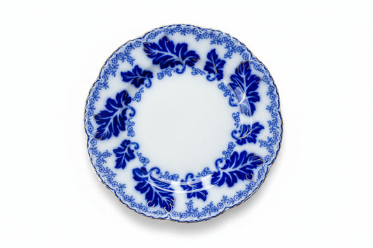 Two antique ironstone plates with a blue flow transfer pattern of leaves and flowers, overlaid with hand-painted gilt details, and scalloped edges.