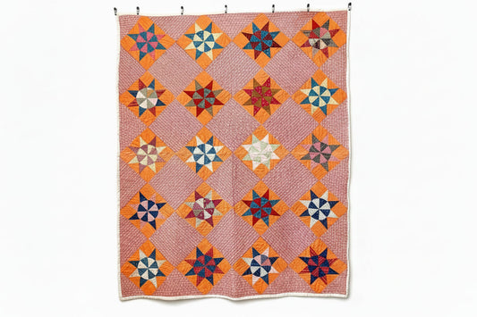 Colorful quilt with star patterns hanging on a white wall