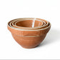 Set of terracotta bowls stacked on a textured surface with a light background