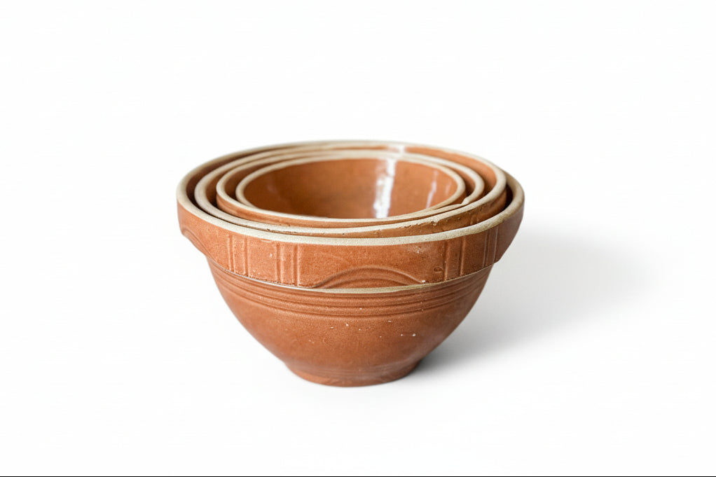 Set of terracotta bowls stacked on a textured surface with a light background