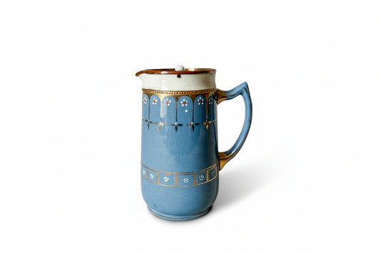 Blue and gold ceramic pitcher with decorative patterns on a textured surface