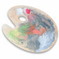 Paint palette with colorful paint strokes on a wooden surface