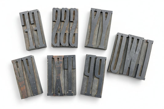 A collection of vintage wooden letterpress blocks arranged on a surface, with varying heights and widths, displaying natural wood color and patina.